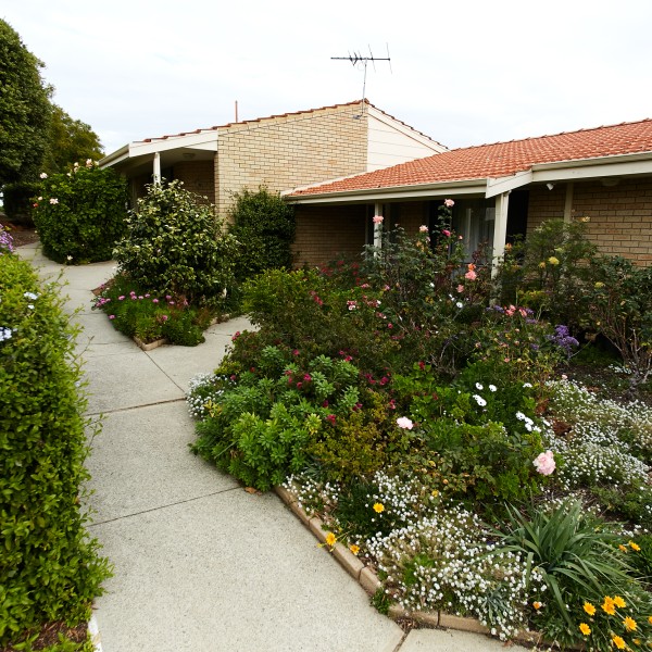 Walkway of Villa Maria retirement village lined with lush plants and colourful flowers