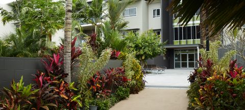 Main entrance of Coral Sea Gardens Retirement Village showcasing lush tropical garden