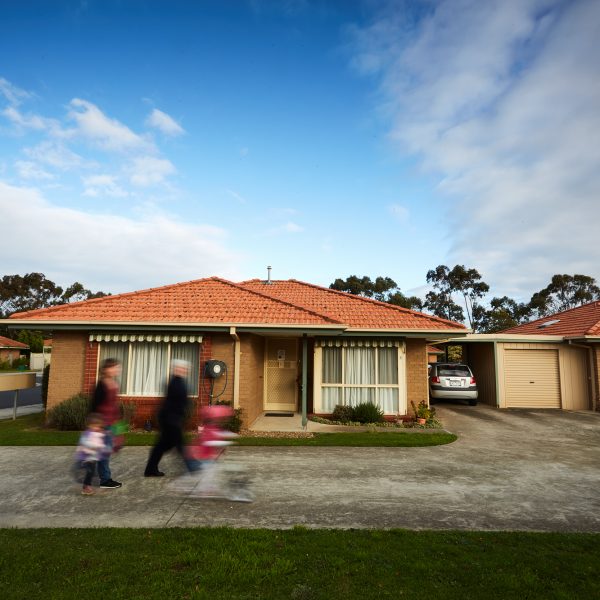 Brick units at Mercy Place Rice Village retirement with blurred resident and family walking past