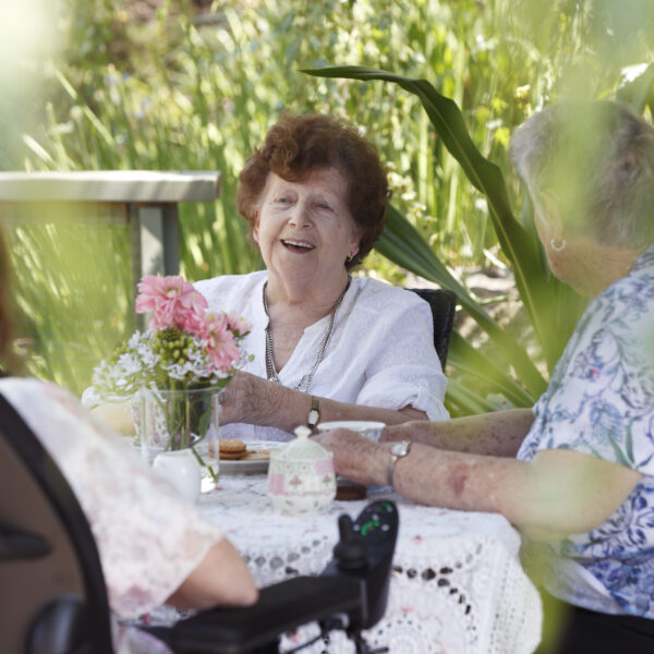 Female residents at Villa Maria laughing and enjoying afternoon tea outside