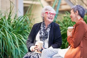 Residents of Coral Sea Gardens Retirement Village sitting outside, having coffee, and smiling