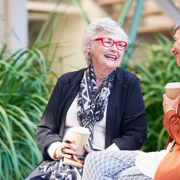 Residents of Coral Sea Gardens Retirement Village sitting outside, having coffee, and smiling
