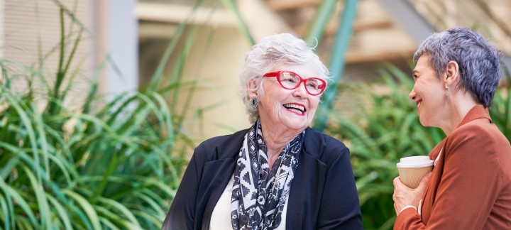 Residents of Coral Sea Gardens Retirement Village sitting outside, having coffee, and smiling
