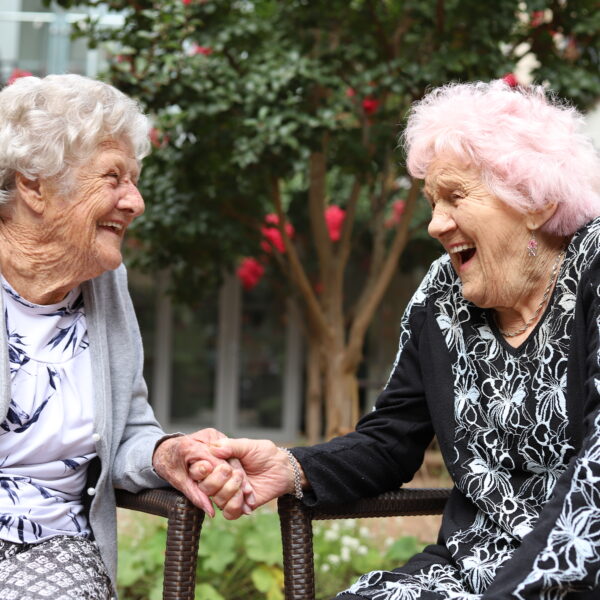 Two residents laughing and holding hands at Mercy Place Rice Village
