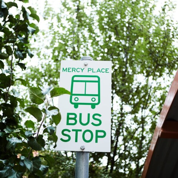 Bus stop sign with green text outside Wesley Grange retirement village